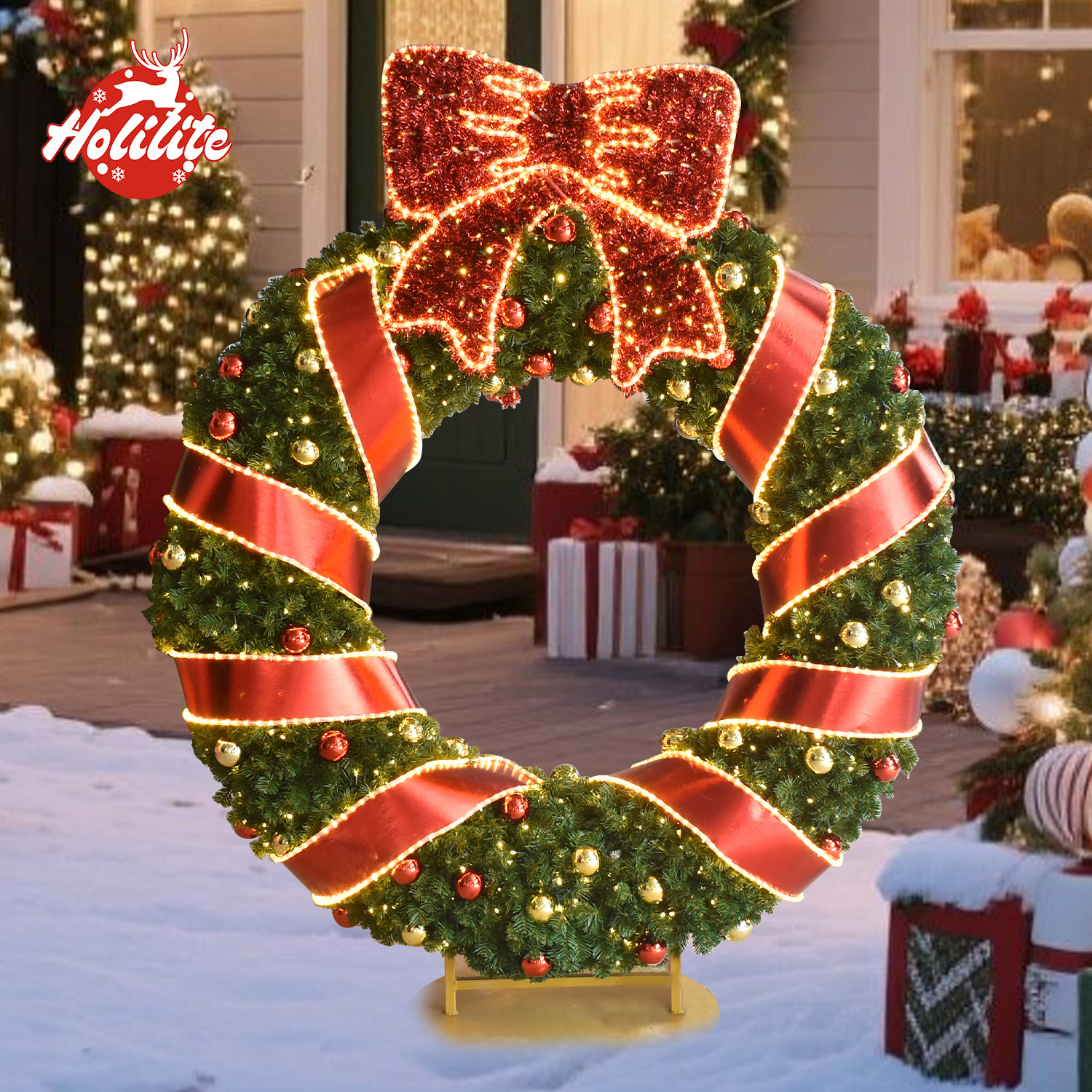 Outdoor holiday wreath entrance decoration with illuminated red bow, green pine branches and red gold ornaments