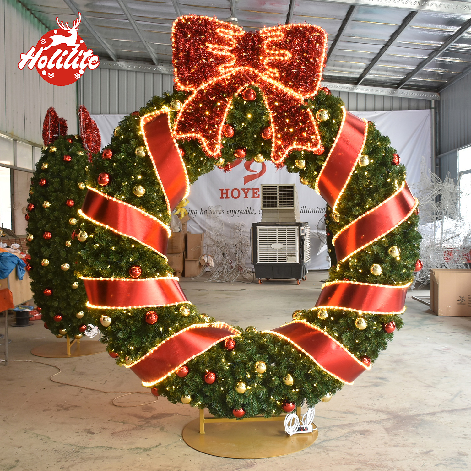 Luxury Christmas wreath arch wrapped with red ribbon, topped with a glitter bow and accented by warm white lights